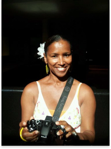 A woman holding a camera in front of a wall.