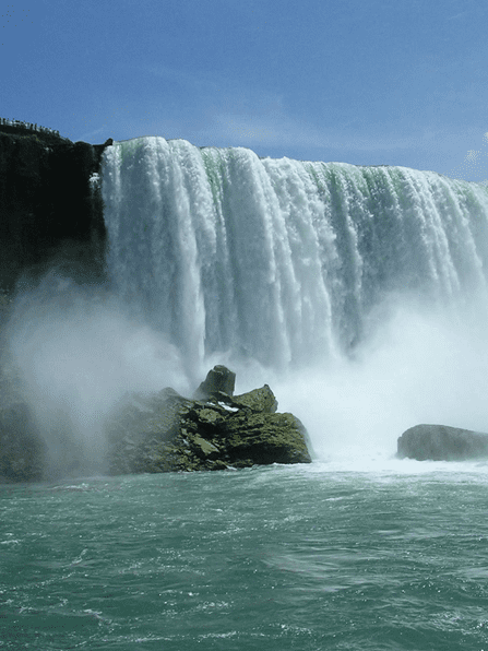 A waterfall with water pouring over it and rocks in the foreground.