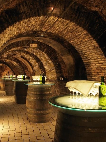 A room with many barrels and bottles of wine